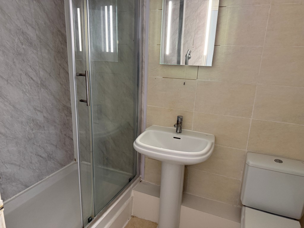 Lot: 135 - TWO-BEDROOM FLAT JUST OFF THE SEAFRONT - White shower unit with sink and WC